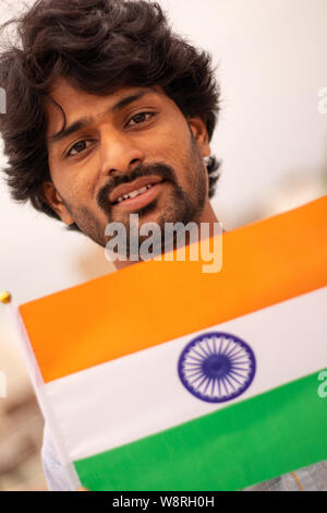 Portrait d'un jeune Indien man holding drapeau indien en robe traditionnelle indienne. Banque D'Images