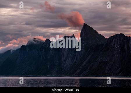 Montagne impressionnante gamme de Segla sur un fjord à minuit par temps nuageux ciel coloré, Senja, Norvège Banque D'Images