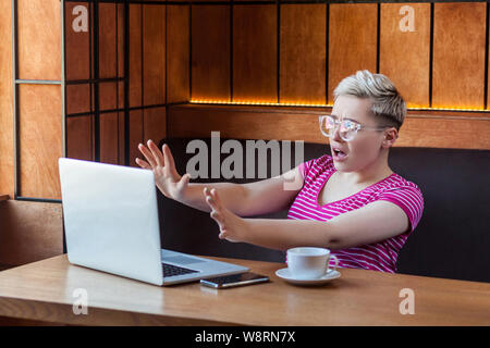 Stop ! Vue de côté portrait de jeune fille peur émotionnelle freelancer est assis dans un café et crier à l'laptope cause fait une grosse erreur avec soulevées Banque D'Images