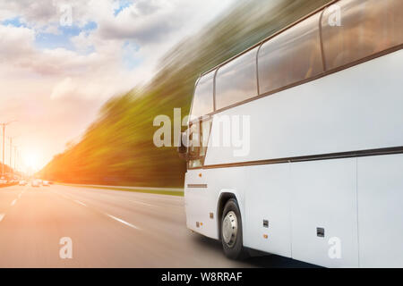 Grand luxe confortable bus touristique en voiture à travers l'autoroute par jour ensoleillé. Route floue. Concept de tourisme de voyage et d'autocar. Trajet et Banque D'Images