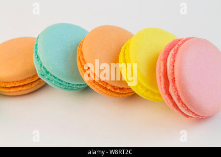 La pâtisserie française cookies macarons cupcake close-up. Multi-macarons couleur sur fond blanc, jaune rose bleu macaroni pâte d'amande avec creme fillin Banque D'Images