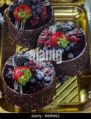 Les gâteaux au chocolat sur une fenêtre ronde, pâtisserie gâteau au chocolat aux fruits rouges, framboises, mûres, bleuets, mûres, groseilles et powdere Banque D'Images