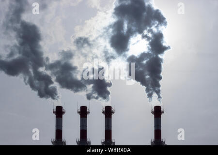 Les tuyaux de silhouettes sombres émettant de la vapeur dans l'atmosphère. Le smog fumée vapeur de tourbillonnantes tubes industriels. La pollution de l'environnement atmosphérique, Banque D'Images