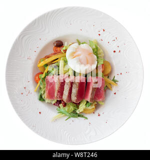 De salade niçoise au thon poêlée de pommes de terre, rare, mélange de salade et oeuf poché en plaque blanche, isolated on white Banque D'Images