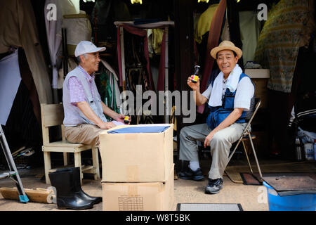 Tokyo / Japon - 31 juillet 2019 - quartier Asakusa. Deux hommes, les propriétaires de boutiques, s'asseoir dans la chaleur en prenant une boisson rafraîchissante et posant pour la caméra. Banque D'Images