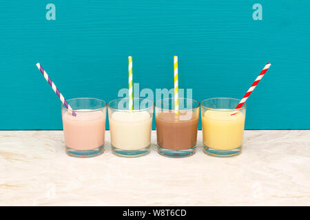 Milkshakes à saveur de fraise -, de chocolat et de banane - lait crémeux et frais avec des pailles en papier rétro verres en verre avec un fond bleu sarcelle Banque D'Images