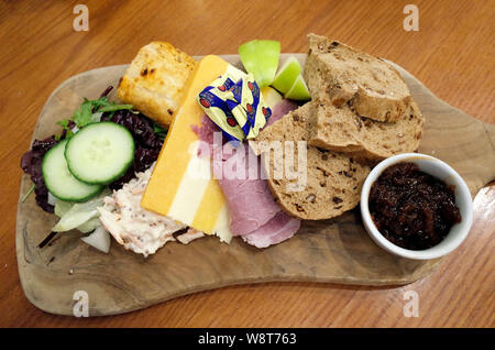 Ploughman's Lunch snack beurre Pain Saucisse jambon fromage tranches de pomme de chou cornichon brun et les feuilles de salade sur planche de bois Banque D'Images