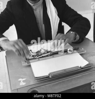 Années 1960, historiques, l'homme arabe assis à un bureau à l'aide d'une pièce d'équipement pour le braille, un système de lecture utilisés par les personnes ayant une déficience visuelle. Banque D'Images