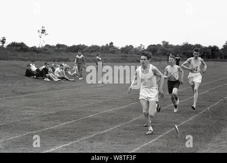 Années 1950, historiques, les athlètes masculins amateur tournant à l'extérieur dans une course sur une piste d'herbe, England, UK. Banque D'Images