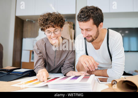 Deux jeunes professionnels créateurs de mode à la recherche à l'un des échantillons de couleur dans le catalogue Banque D'Images