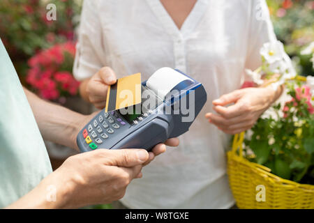 À l'aide de l'acheteur de sexe féminin contemporain carte de crédit pour payer pour des fleurs en pot Banque D'Images