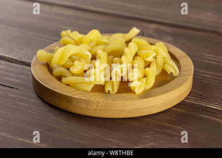 Lot de pâtes crues gemelli pour plaque de bambou sur bois marron foncé Banque D'Images