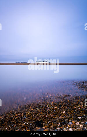 Une longue exposition des nuages et de l'eau à Shingle Street dans le Suffolk. L'eau a pris un effet laiteux et il y a beaucoup d'espace négatif Banque D'Images