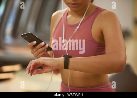 Mid section portrait of young woman checking smartwatch lors de l'entraînement en salle de sport, copy space Banque D'Images