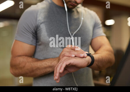 Mid section portrait de l'homme contrôle smartwatch méconnaissable pendant l'entraînement en salle de sport, copy space Banque D'Images