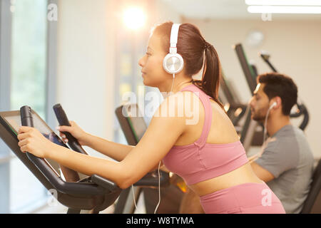 Side view portrait of young woman wearing headphones exerçant en salle de sport, copy space Banque D'Images