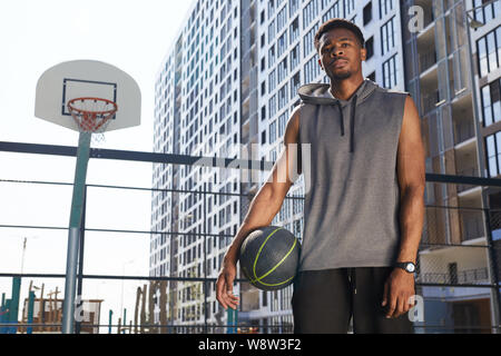 Portrait de joueur de basket-ball d'origine afro-américaine de permanent dans une cour, copy space Banque D'Images