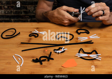 Tuyau d'Halloween-filtre papier de construction et l'artisanat avec les chats noirs. Les mains d'un homme dans l'image indique la progression de l'artisanat projet un peu. Banque D'Images