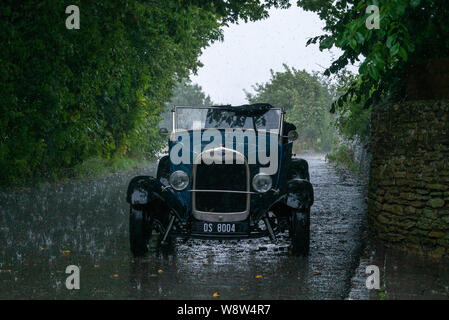 1929 Ford Roadster chauffeur pris dans de fortes pluies, Frome Somerset UK Banque D'Images