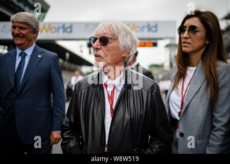 Bernie Ecclestone (C), Président émérite de la formule un groupe et son épouse Fabiana Flosi (R) Promenade à travers la grille de départ avant la course de Grand Prix MotoGP autrichien. Banque D'Images