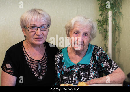 Une vieille femme avec sa fille adulte assis à la maison pose pour portrait. Banque D'Images