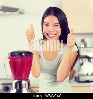 Femme faisant Smoothie smoothies de fruits et baies giving Thumbs up heureux par blender. Concept de vie saine alimentation portrait de belle jeune femme préparer le mélange boisson fraises, framboises