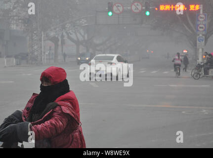 --FILE--un cycliste couvrant sa bouche et le nez avec un foulard se déplace sur une route dans le smog lourd dans la ville de Handan, province de Hebei, Chine du nord 21 Décembre 2013 Banque D'Images