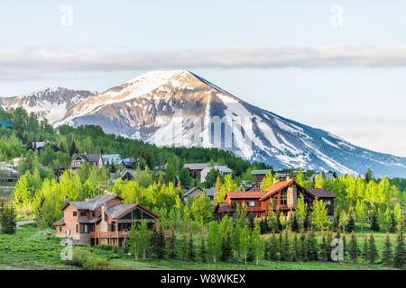 Mount Crested Butte, Colorado village en été avec des maisons en bois par le lever du soleil sur les collines avec des arbres verts Banque D'Images