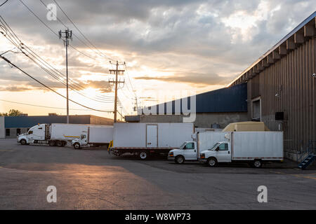 Les camions de livraison en attente et cars devant un petit bâtiment d'entreprise Banque D'Images