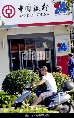 --FILE--Un homme chevauche son vélo électrique passé une succursale de la Banque de Chine (BOC) en ville, à l'est Chinas Dexing Jiangxi province, 23 juillet 2014. Banque de Chine Banque D'Images