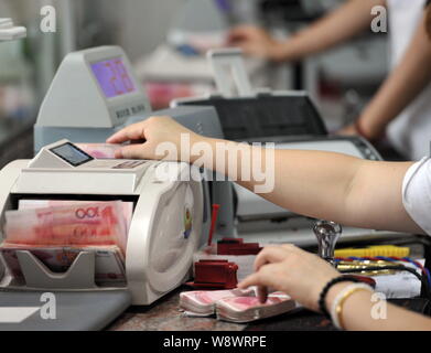 --FILE--un greffier chinois utilise une machine de comptage de caisse à compter de RMB (renminbi) yuan billets à une succursale de la Banque agricole de Chine à Qionghai city Banque D'Images