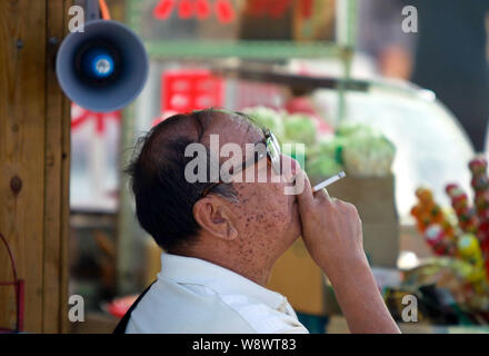 --FILE--un Chinois fume sur une route à Qingdao ctiy, la province de Shandong, Chine de l'Est, le 30 mai 2013. Le chef de l'Organisation mondiale de la Santé a ur Banque D'Images