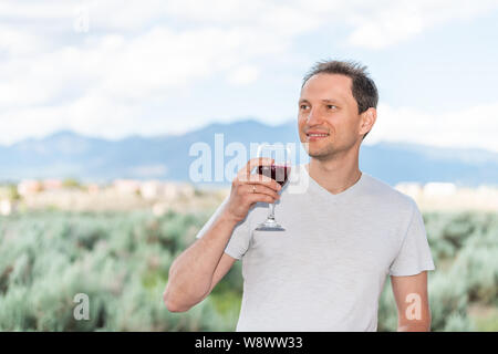 Dégustation de vin rouge l'homme en vue de Taos montagnes Sangre de Cristo de Ranchos de Taos valley dans l'arrière-plan flou d'arrière-cour Banque D'Images