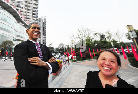 Un piéton passe devant un caoutchouc figure du président américain Barack Obama sur l'affichage à l'extérieur du centre de vente d'une propriété résidentielle dans Luoyan projet Banque D'Images