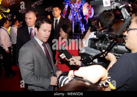 L'acteur américain Mark Wahlberg, à gauche, est interviewé sur le tapis rouge pour la première mondiale de Beijing son nouveau film, Transformers : l'âge d'extinction, en être Banque D'Images