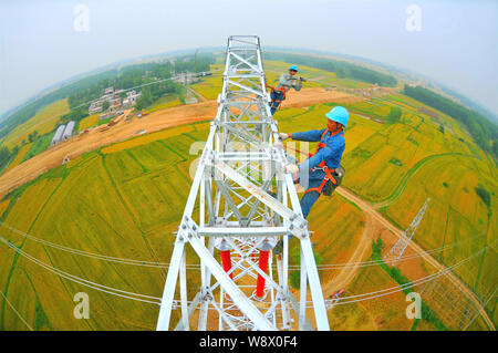 Les travailleurs chinois monter les câbles haute tension sur un pylône de plus de champs dans Lujiagang massive village, ville, comté de Fengyang Xiangzhou District, Foshan City, est de la Chine Banque D'Images