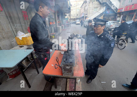 --FILE--Un officier chinois du Bureau municipal de Pékin de l'Administration de la ville et de l'application de la loi du vendeur un décrochage persuade d'enlever son barbecue Banque D'Images