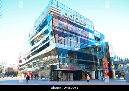 --FILE--piétons passent devant un magasin de vêtements de sport Adidas dans Village Sanlitun, Beijing, Chine, 4 février 2013. La première nouvelle Adidas concept store, un Banque D'Images