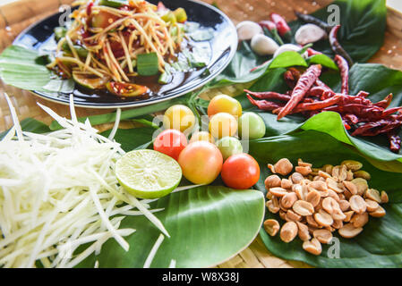 Salade de papaye servi sur table à manger / Salade de papaye verte spicy thai food sur la plaque avec des herbes et épices Ingrédients avec tomate piment ail - arachide Banque D'Images