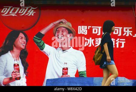 --FILE--un piéton passe devant une publicité pour Coca-Cola à Yichang city, province de Hubei, Chine centrale 13 juin 2014. Ventes et d'une télévision soda Banque D'Images