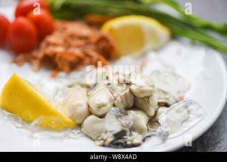 Huîtres fraîches servi sur plaque blanche et de glace / Salade d'Huîtres au citron et aux herbes dans le restaurant de fruits de mer Banque D'Images