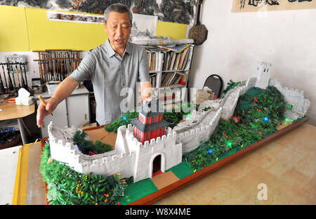 68 ans retraité chinois Wang Desheng parle comme il met la touche finale sur sa miniature faite maison d'une section de la Grande Muraille du Qi à Qingdao cit Banque D'Images