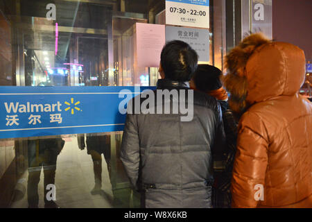 --FILE--Les gens regardent un avis de Walmart à un supermarché Walmart dans l'est de la ville de Yancheng, province de Jiangsu, Chine, 6 mars 2014. Les magasins Wal-Mart Banque D'Images