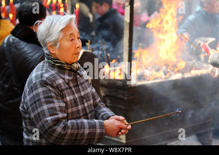 Une vieille femme chinoise brûle encens à prier pour la richesse et l'adoration du dieu de la richesse sur le cinquième jour du Nouvel An chinois au Tianning Banque D'Images