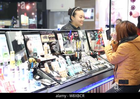 --FILE--un client essaye de cosmétiques à un centre commercial dans la ville de Xuchang, province de Henan Chine centrale, 14 décembre 2013. Les consommateurs chinois peuvent pa Banque D'Images