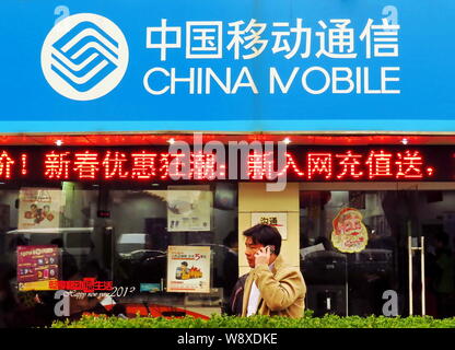 --FILE--un piéton parle sur son téléphone mobile alors qu'il passe devant une succursale de China Mobile à Shanghai, Chine, 23 février 2014. China Mobile Ltd., th Banque D'Images