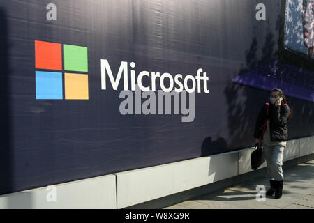 --FILE--un piéton parle sur son téléphone portable alors qu'elle passe devant une publicité pour Microsoft Surface pro 2 à Shanghai, Chine, 12 décembre 2013. Banque D'Images