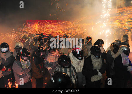 --FILE--visiteurs portant des casques rester près de l'explosion de fusées bouteille d'obtenir pulvérisé par le feu d'étincelles pendant le Festival des fusées Yanshui Beehive Banque D'Images