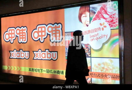 --FILE--un piéton passe devant une publicité pour la chaîne Xiabu Xiabu hotpot chinois à Shanghai, Chine, le 28 décembre 2011. Xiabuxiabu Mana traiteur Banque D'Images