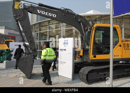 --FILE--un employé chinois passe devant un excavateur Volvo fabriqué par Volvo Construction Equipment lors de l'édition 2010 Salon International des Cons Banque D'Images